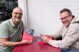 Andreas Ollmann und Sebastian Keil präsentieren lachend ihr Buch "Gestaltungslust" an einem Tisch mit mehreren Exemplaren